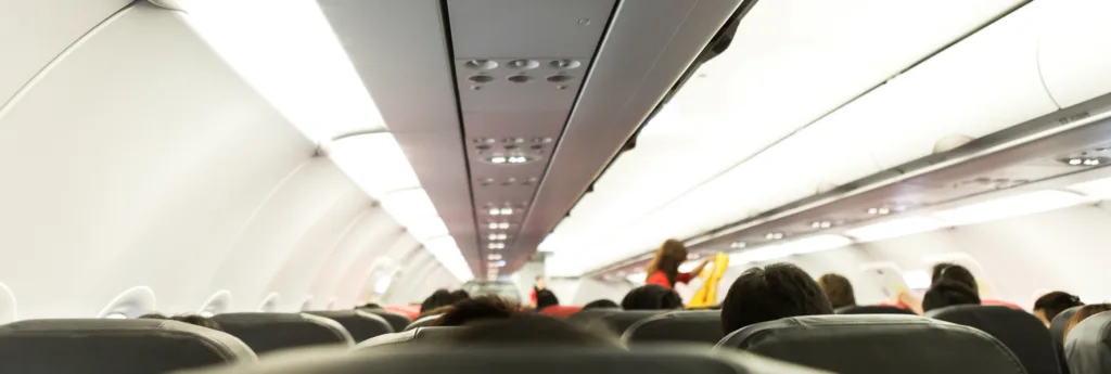 View inside an airplane cabin with rows of seats and overhead compartments.