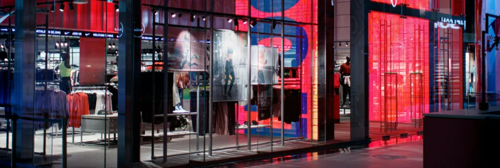 Interior view of a modern retail store with vibrant red and blue LED lighting, displaying clothing on racks and manne mannequins.