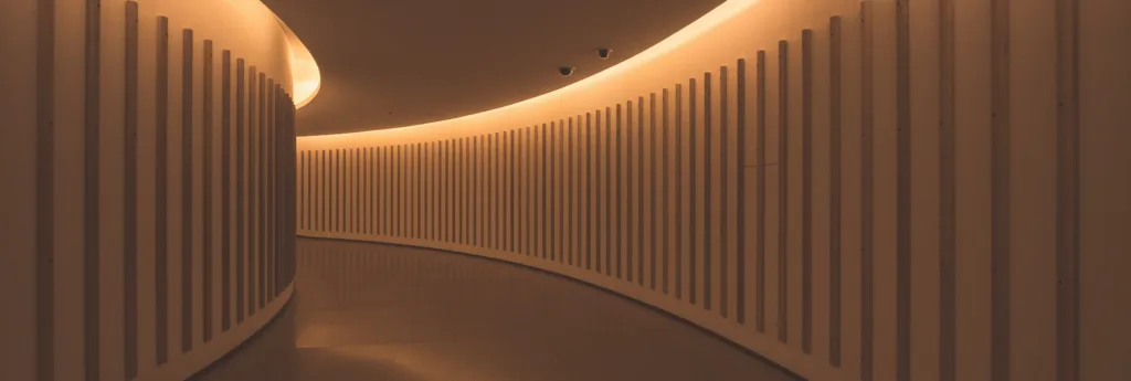 Curved, modern hallway with warm, indirect lighting.