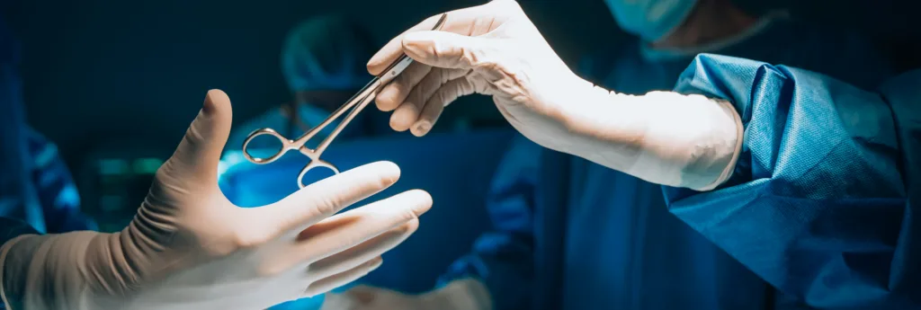A person in a full white hazmat suit, blue gloves, and a face shield handles a clear bag with colorful items in a laboratory.