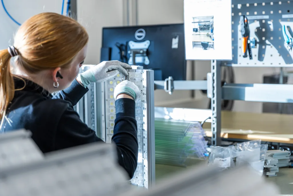 Person in gloves assembling LED components onto a panel.