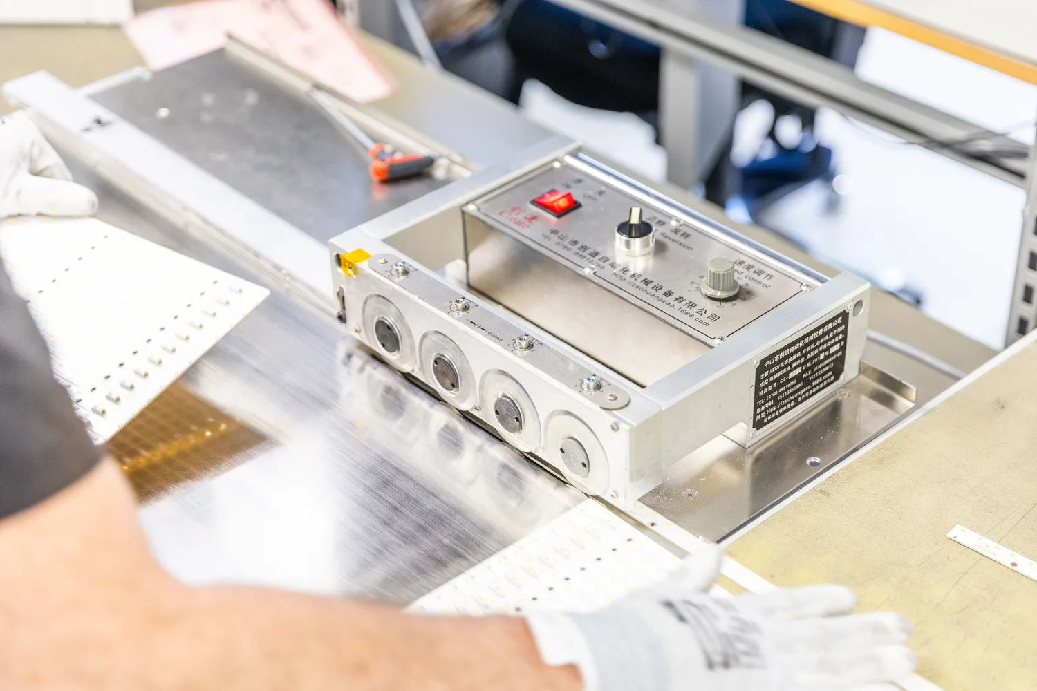 Close-up of an industrial machine with Chinese labels and a red power button, used for processing circuit boards or electronic components.