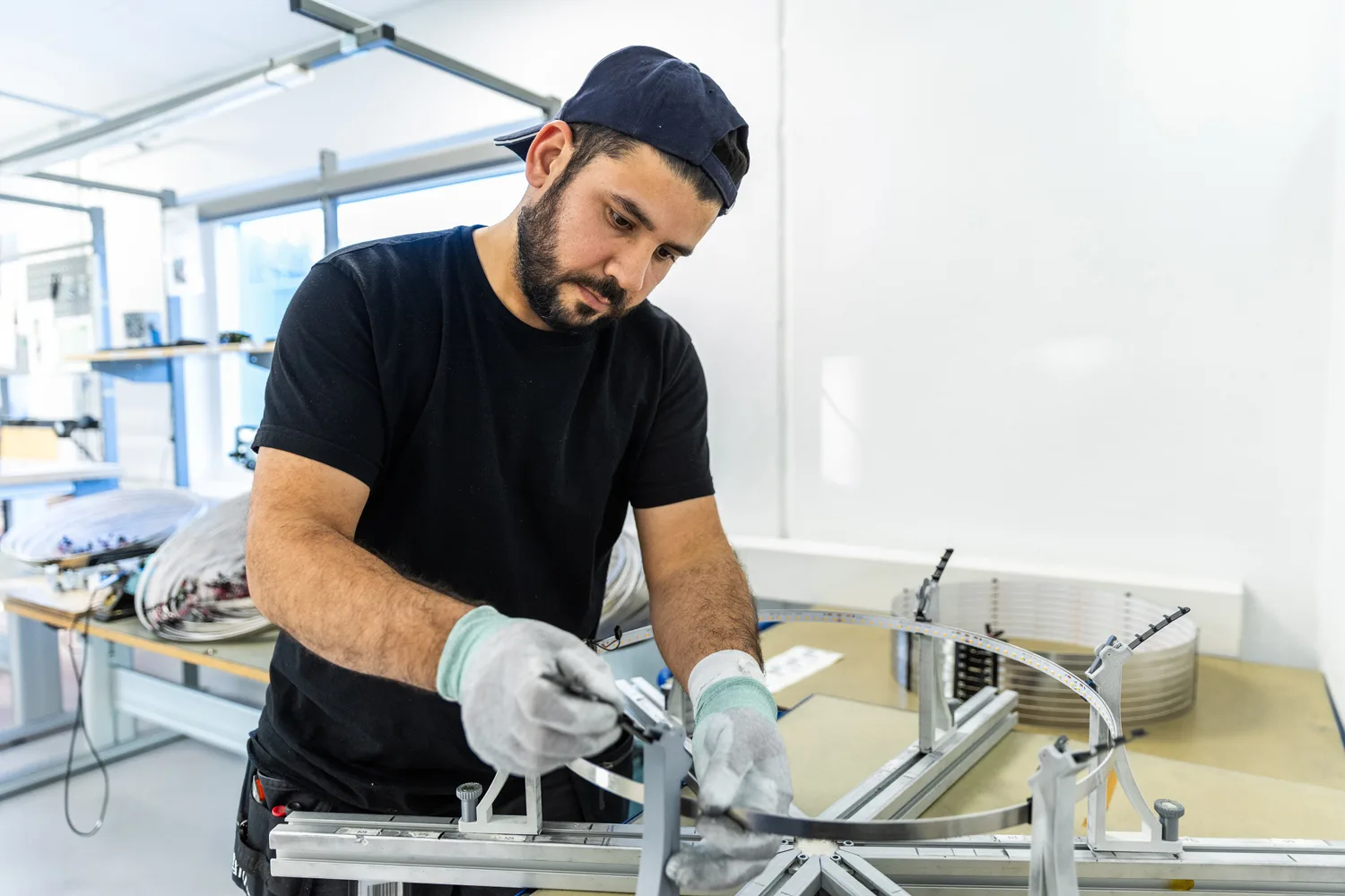 Industrial worker meticulously bending a component on a jig, demonstrating precision in a clean workshop environment.