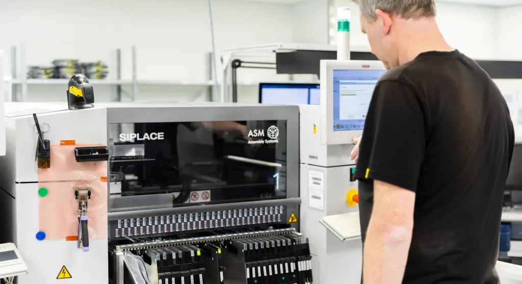 A person operates an industrial assembly machine in a manufacturing facility.